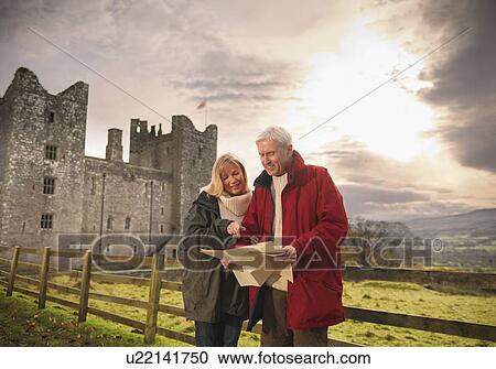 Stock Image - Older couple reading map by castle. Fotosearch