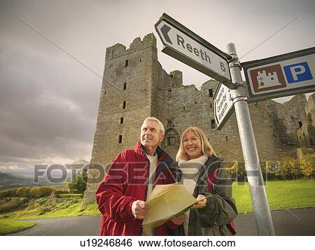 Stock Photograph - Older couple reading map on rural road. Fotosearch