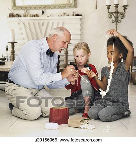 Stock Photograph - Older man and girls stringing popcorn. Fotosearch