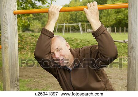 Older man hanging from jungle gym View Large Photo Image Stock Photo - Older man hanging from jungle gym. Fotosearch