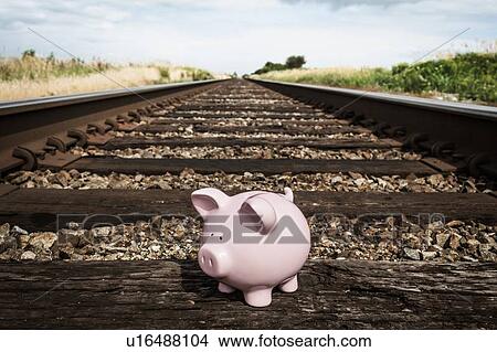 Picture - Piggy bank on railroad tracks. Fotosearch