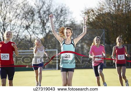 Stock Image - Runner crossing finish line in field. Fotosearch