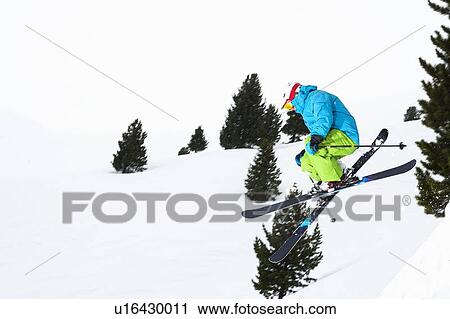 Stock Image - Skier jumping on snowy slope. Fotosearch
