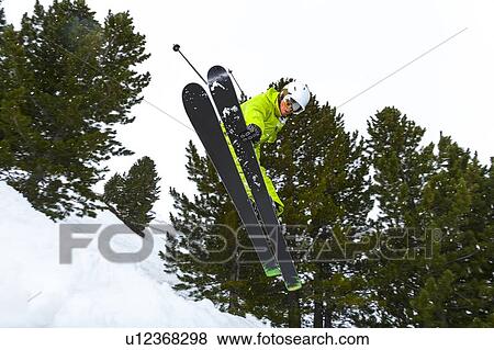 Stock Photo - Skier jumping on snowy slope. Fotosearch