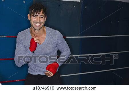 Stock Image - Smiling boxer standing in ring. Fotosearch