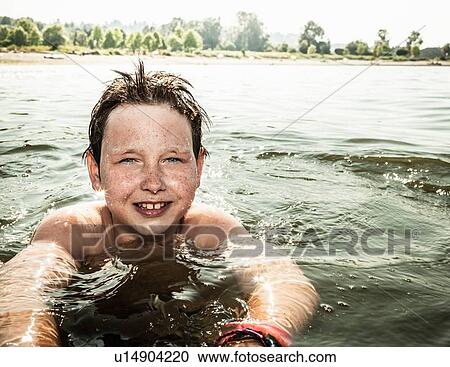 Stock Image - Smiling boy swimming in lake. Fotosearch
