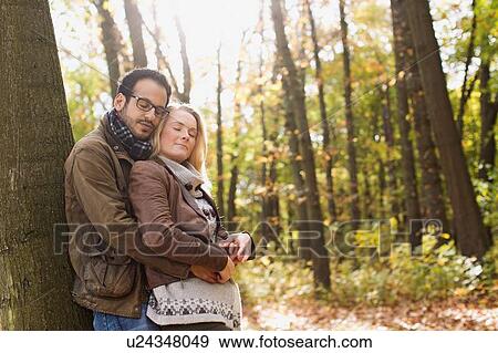 Stock Photo - Smiling couple hugging in forest. Fotosearch