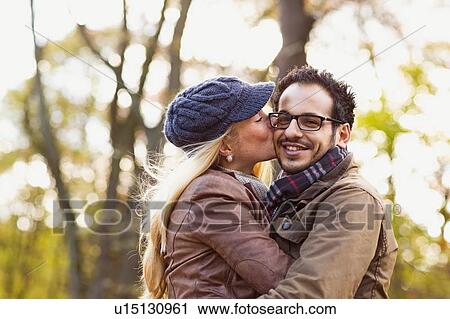 Stock Image - Smiling couple kissing in forest. Fotosearch