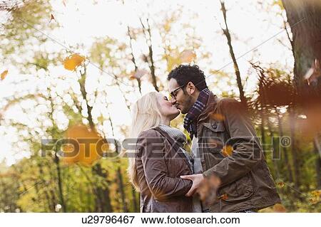 Stock Photo - Smiling couple kissing in forest. Fotosearch