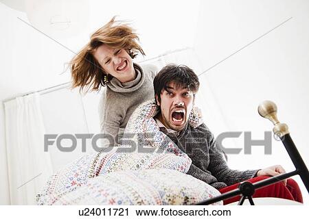 Stock Image - Smiling couple playing in bed. Fotosearch