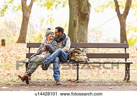 Smiling couple sitting on park bench View Large Photo Image Stock Image - Smiling couple sitting on park bench. Fotosearch