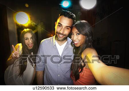 Stock Image - Smiling friends taking picture together. Fotosearch