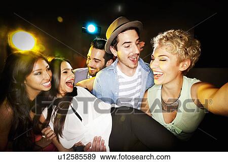 Stock Photo - Smiling friends taking picture together. Fotosearch