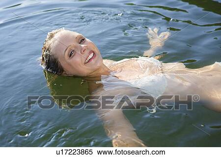 Smiling woman floating in still lake View Large Photo Image Stock Photography - Smiling woman floating in still lake. Fotosearch