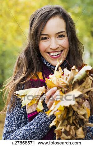 Smiling woman holding autumn leaves View Large Photo Image Stock Image - Smiling woman holding autumn leaves. Fotosearch