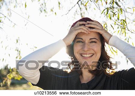 Stock Photograph - Smiling woman holding her forehead. Fotosearch
