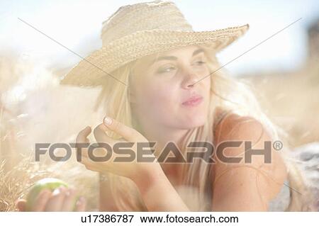 Stock Photo - Smiling woman laying in tall grass. Fotosearch