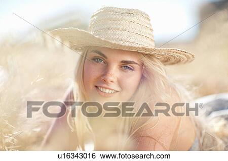 Stock Photograph - Smiling woman laying in tall grass. Fotosearch