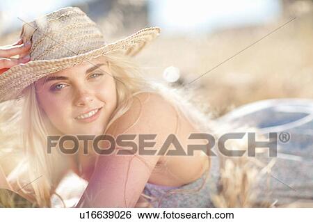 Stock Photograph - Smiling woman laying in tall grass. Fotosearch