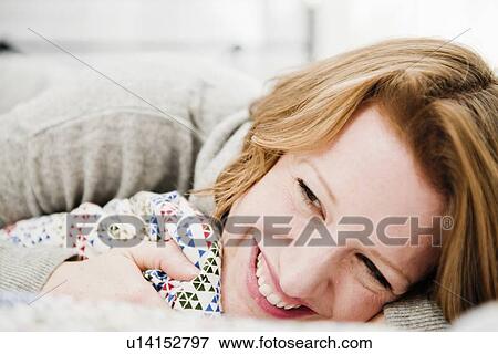 Stock Photo - Smiling woman laying on bed. Fotosearch