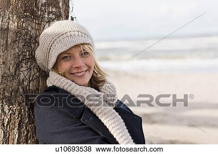 Smiling woman leaning against log View Large Photo Image Stock Photo - Smiling woman leaning against log. Fotosearch
