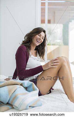 Smiling woman sitting on bed View Large Photo Image Stock Photo - Smiling woman sitting on bed. Fotosearch