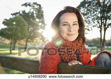 Smiling woman sitting on park bench View Large Photo Image Stock Image - Smiling woman sitting on park bench. Fotosearch