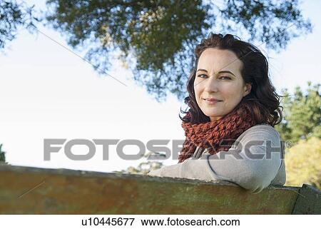 Smiling woman sitting on park bench View Large Photo Image Stock Photo - Smiling woman sitting on park bench. Fotosearch