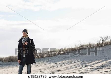 Stock Photograph - Smiling woman standing on beach. Fotosearch