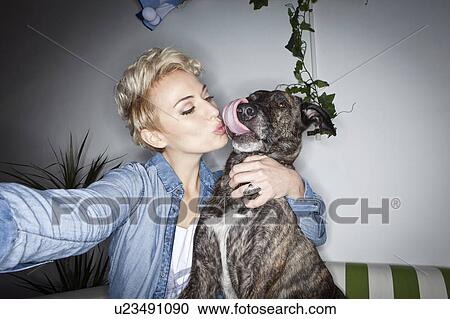 Stock Image - Smiling woman taking picture with dog. Fotosearch