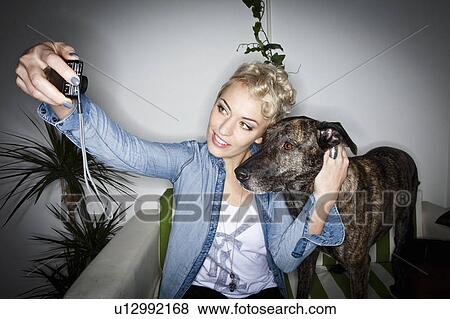 Stock Photo - Smiling woman taking picture with dog. Fotosearch