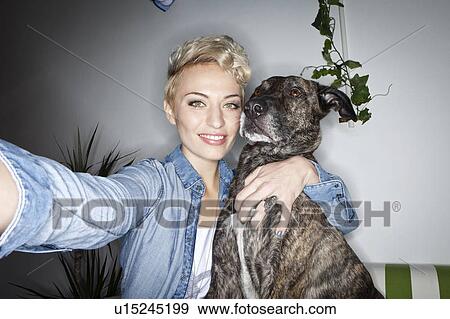 Stock Photo - Smiling woman taking picture with dog. Fotosearch
