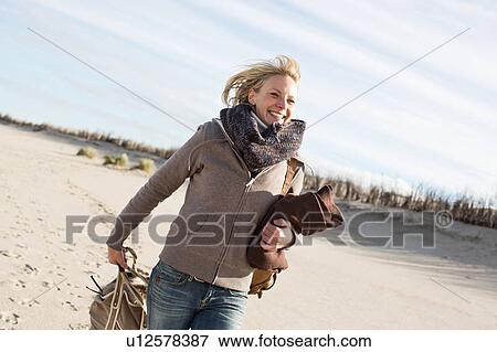 Smiling woman walking on beach View Large Photo Image Stock Photo - Smiling woman walking on beach. Fotosearch