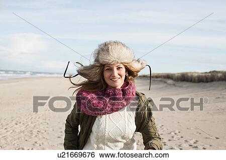 Stock Photograph - Smiling woman walking on beach. Fotosearch