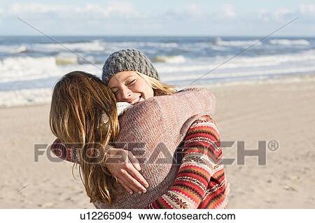 Picture - Smiling women hugging on beach. Fotosearch
