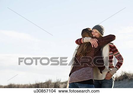 Picture - Smiling women hugging on beach. Fotosearch