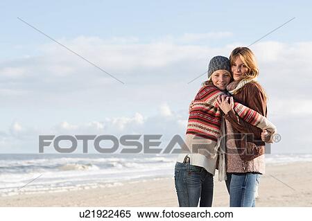 Stock Photography - Smiling women hugging on beach. Fotosearch