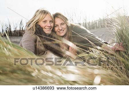 Stock Image - Smiling women relaxing on beach. Fotosearch