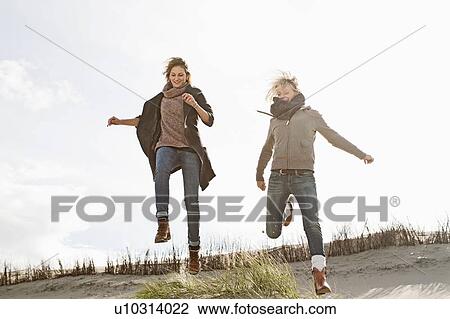 Stock Image - Smiling women running on beach. Fotosearch