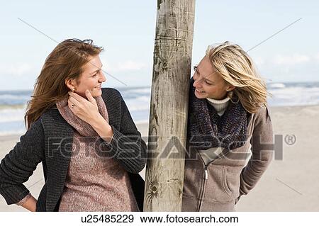 Smiling women talking on beach View Large Photo Image Stock Photo - Smiling women talking on beach. Fotosearch