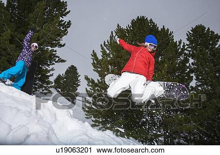 Stock Image - Snowboarder jumping on snowy slope. Fotosearch