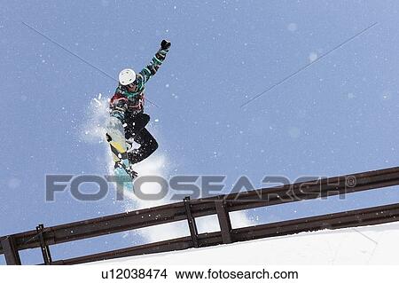 Picture - Snowboarder jumping over metal railing. Fotosearch