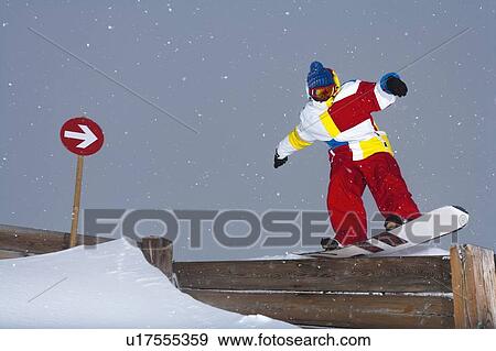 Stock Photo - Snowboarder sliding on wooden fence. Fotosearch
