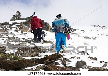 Snowboarders hiking on rocky slope View Large Photo Image Stock Photo - Snowboarders hiking on rocky slope. Fotosearch
