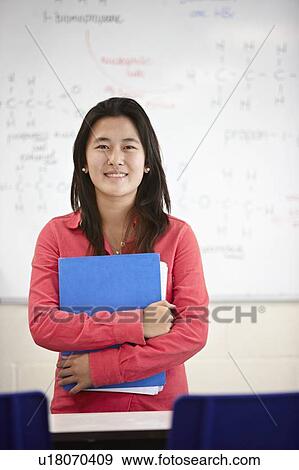 Stock Photo - Student holding book in classroom. Fotosearch
