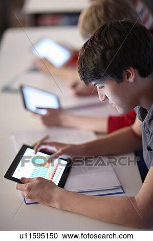 Stock Image - Students using tablet computers in class. Fotosearch