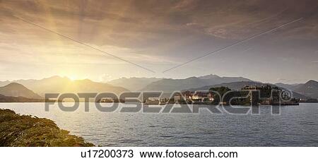 Stock Image - Sun rising over rural village and lake. Fotosearch