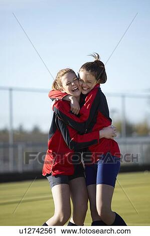 Stock Image - Team members hugging on field. Fotosearch