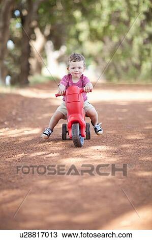 Toddler boy riding toy on dirt road View Large Photo Image Stock Image - Toddler boy riding toy on dirt road. Fotosearch
