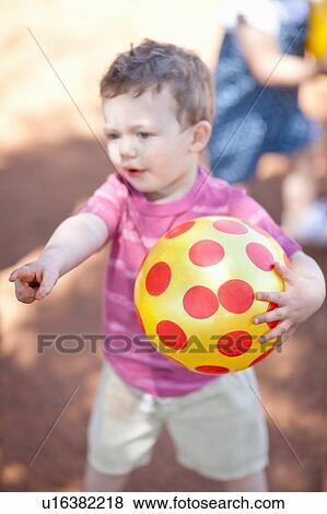 Stock Photo - Toddler boy with ball on dirt road. Fotosearch